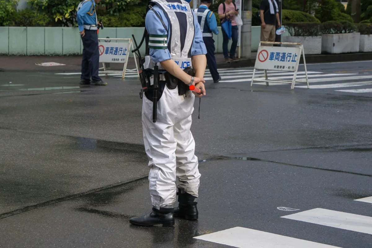 警備員が交差点に立っている写真。